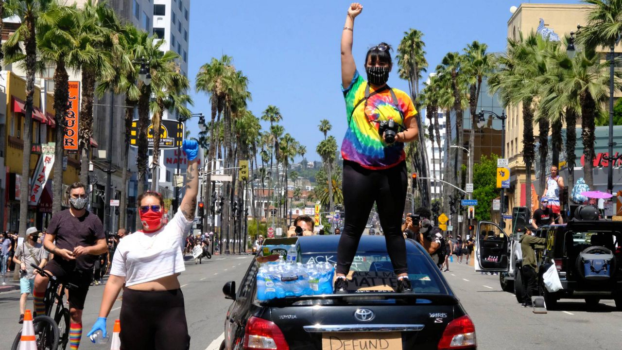 In this, June 14, 2020, file photo, protesters raise their fists at a march, organized by black LGBTQ leaders in Los Angeles. (AP Photo/Paula Munoz)
