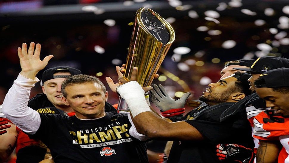 FILE - This Jan. 12, 2015, file photo shows Ohio State head coach Urban Meyer and Ezekiel Elliott celebrating after the NCAA college football playoff championship game against Oregon, in Arlington, Texas. Meyer, the highly successful coach who won three national championships and sparked controversy and criticism this season for his handling of domestic violence allegations against a now-fired assistant, will retire after the Rose Bowl, the university announced Tuesday, Dec. 4, 2018. (AP Photo/Eric Gay, File)