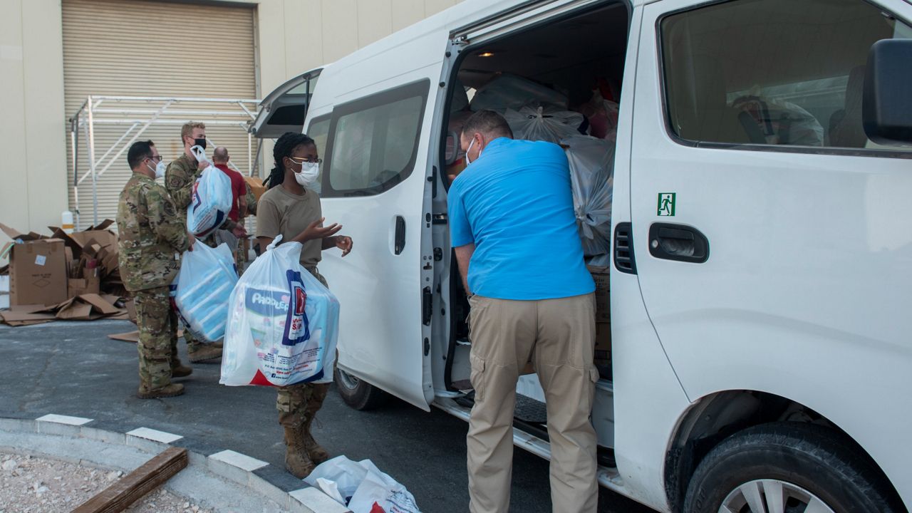In this Aug. 10, 2021, photo provided by the U.S. Marine Corps, Members from the 379th Air Expeditionary Wing carry donations for Afghanistan evacuees into a hangar in the CENTCOM area of responsibility. (Airman 1st Class Kylie Barrow/U.S. Marine Corps via AP)