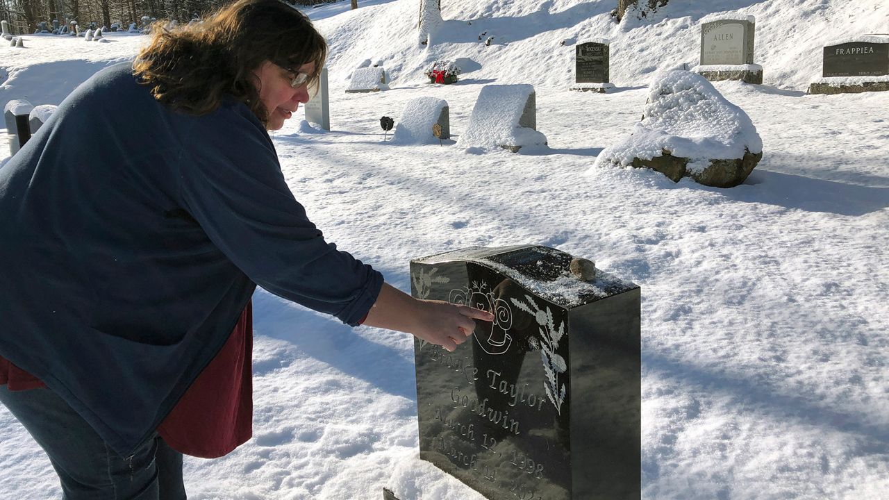 Deb Walker, of Chester, Vt., visits the grave of her daughter Brooke Goodwin, Thursday, Dec. 9, 2021, in Chester. Goodwin, 23, died in March of 2021 of a fatal overdose of the powerful opioid fentanyl and xylazine.  (AP Photo/Lisa Rathke, File)
