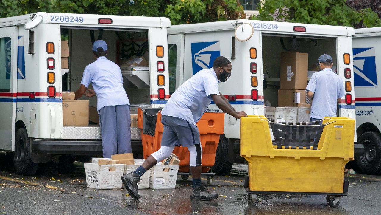 In this July 31, 2020, file photo, letter carriers load mail trucks for deliveries at a U.S. Postal Service facility in McLean, Va. 