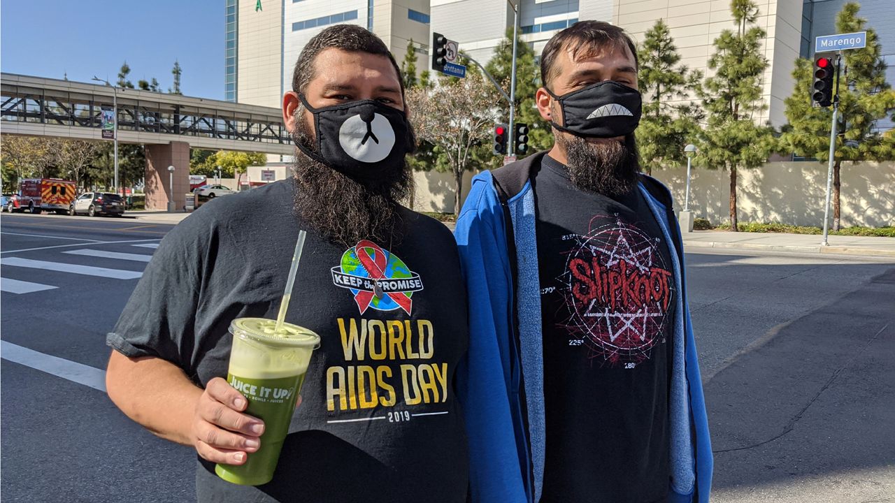 People wear decorated face masks as they walk across the Los Angeles County + USC Medical Center in Los Angeles Monday, March 30, 2020. (AP Photo/Damian Dovarganes)