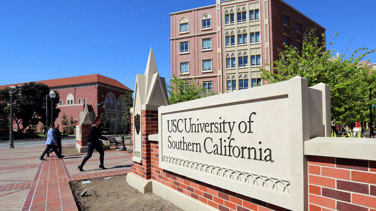 In this March 12, 2019, file photo, people walk at the University Village area of the University of Southern California in Los Angeles. (AP Photo/Reed Saxon)