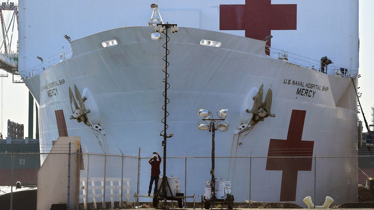 In this March 27, 2020, file photo, a pedestrian takes a picture of the USNS Mercy as it docks at the Port of Los Angeles. (AP Photo/Mark J. Terrill, File)
