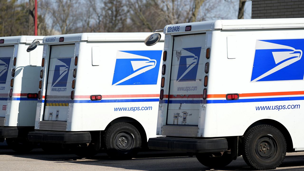 U.S. Postal Service trucks park outside a post office, Jan. 29, 2024, in Wheeling, Ill. The number of robberies of postal carriers grew again in 2023 and the number of injuries nearly doubled, even as the U.S. Postal Service launched crackdown aimed at addressing postal crime. (AP Photo/Nam Y. Huh, File)