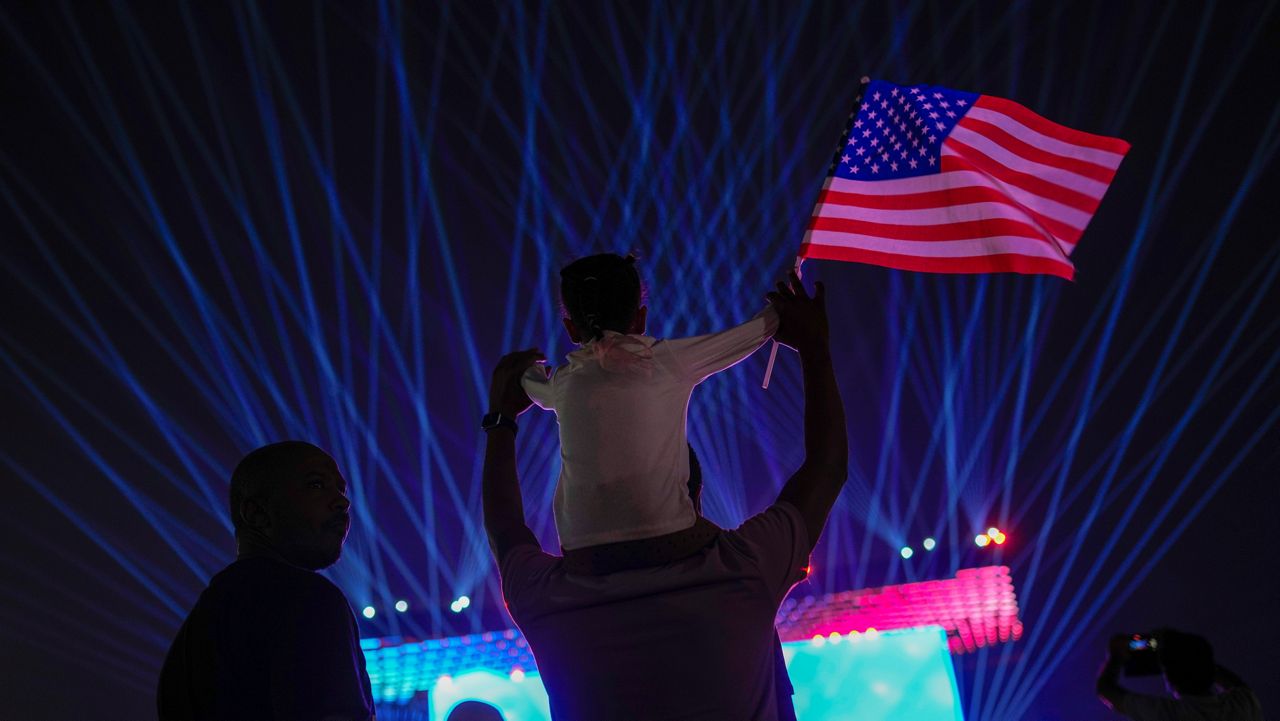 A child waves an U.S. flag as people cheer up in the fan zone prior the opening ceremony of the World Cup, in Doha, Qatar, Sunday, Nov. 20, 2022. (AP Photo/Francisco Seco)