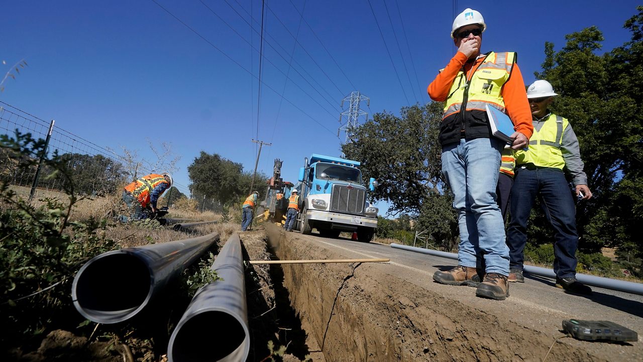 Paul Standen, senior director of underground regional delivery, second from right, and project manager Jeremy Schanaker, right, look on during a tour of a Pacific Gas and Electric crew burying power lines in Vacaville, Calif. on Oct. 11, 2023. (AP Photo/Jeff Chiu)