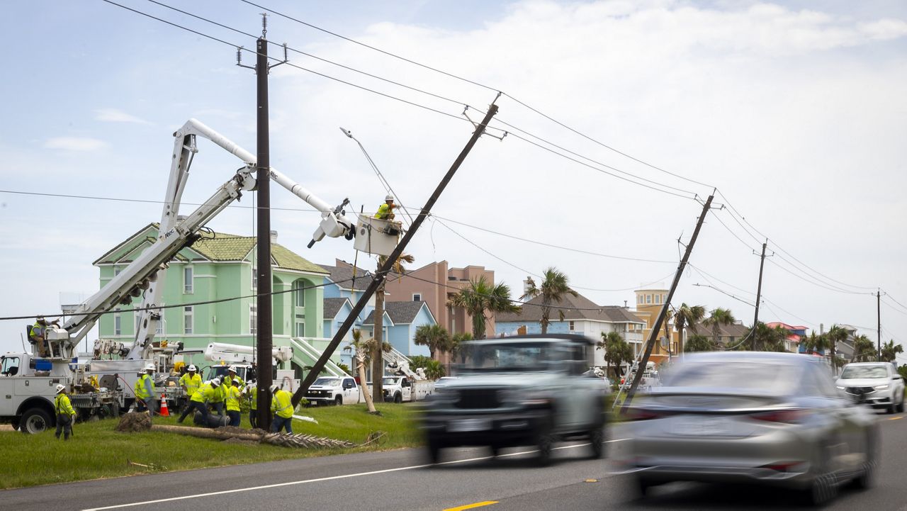 Linemen place a new fiberglass utility pole to replace older, leaning wooden poles along FM 3005 on Galveston Island on Saturday, July 13, 2024. (AP Photo/Annie Mulligan)