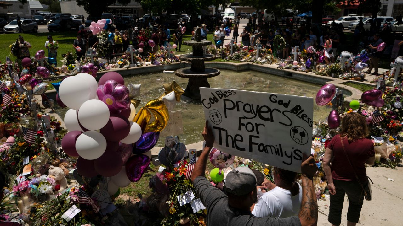 People visit a memorial set up in a town square to honor the victims killed in this week's elementary school shooting in Uvalde, Texas Saturday, May 28, 2022. (AP Photo/Jae C. Hong)