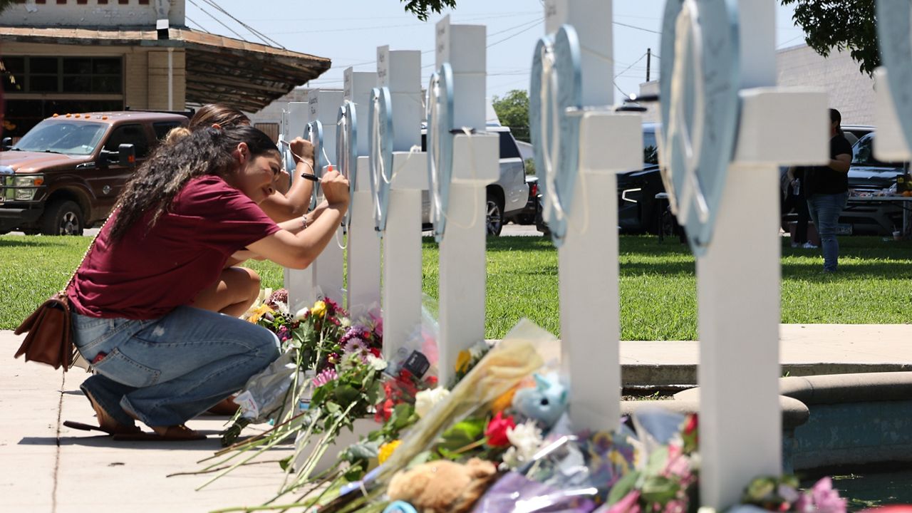 People writing on memorials of the Uvalde shooting in Texas. (AP Images)