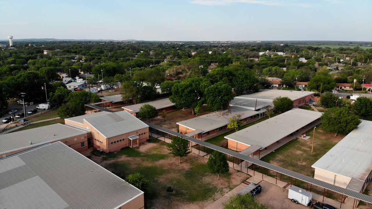 In this aerial image taken with a drone, police and media gather around Robb Elementary School in Uvalde, Texas, on Saturday, May 28, 2022. (AP Photo/Allen G. Breed)