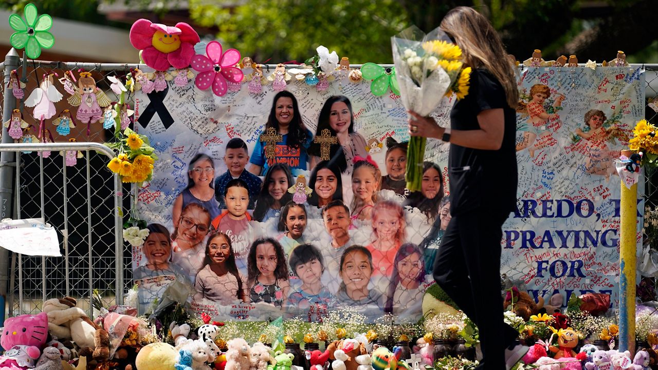 A mourner delivers flowers to a memorial at Robb Elementary School created to honor the victims killed in the recent school shooting, Thursday, June 9, 2022, in Uvalde, Texas. Two teachers and 19 students were killed in the mass shooting. (AP Photo/Eric Gay)