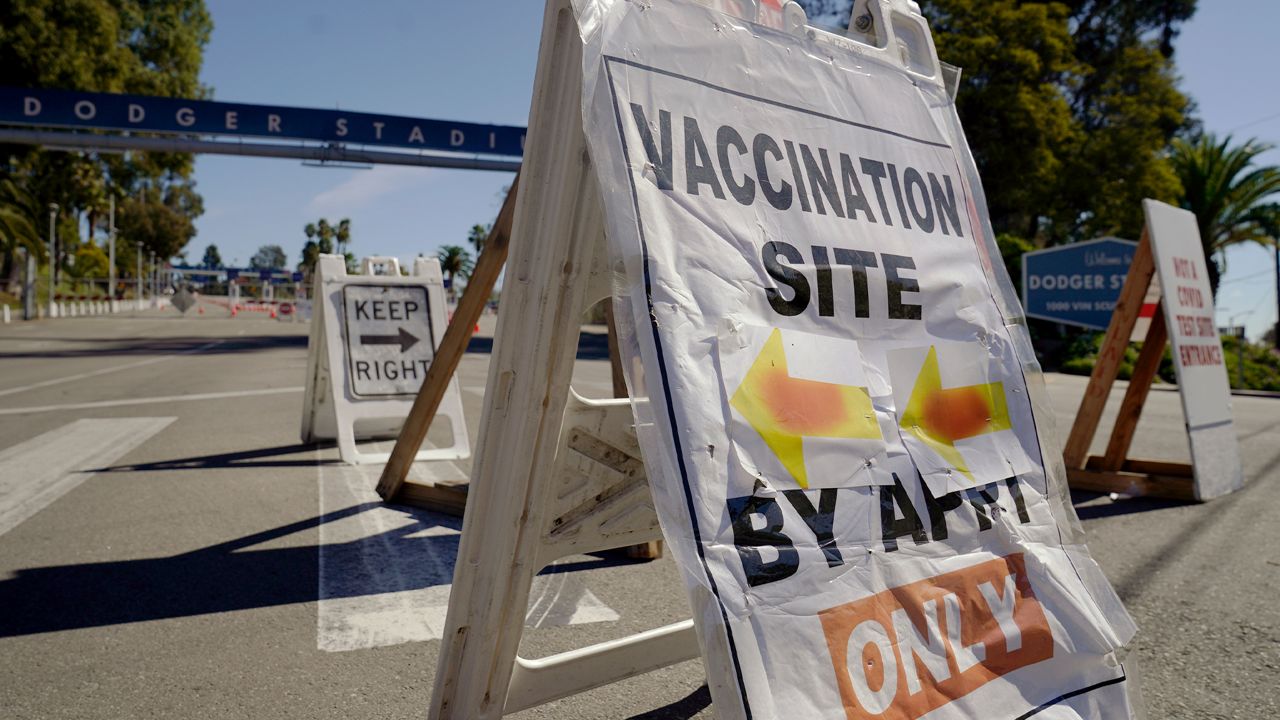Old signs direct motorists to a closed vaccination site at Dodger Stadium, a mass COVID-19 vaccination in Los Angeles, Friday, Feb. 19, 2021. (AP Photo/Damian Dovarganes)