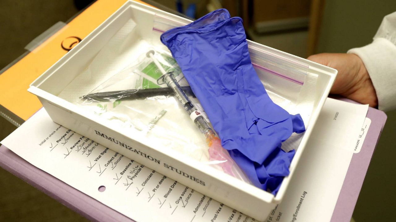 FILE - In this file photo, pharmacist Michael Witte holds a tray with a syringe containing a shot that will be used in the first clinical trial of a potential vaccine for COVID-19. (AP Photo/Ted S. Warren, File)