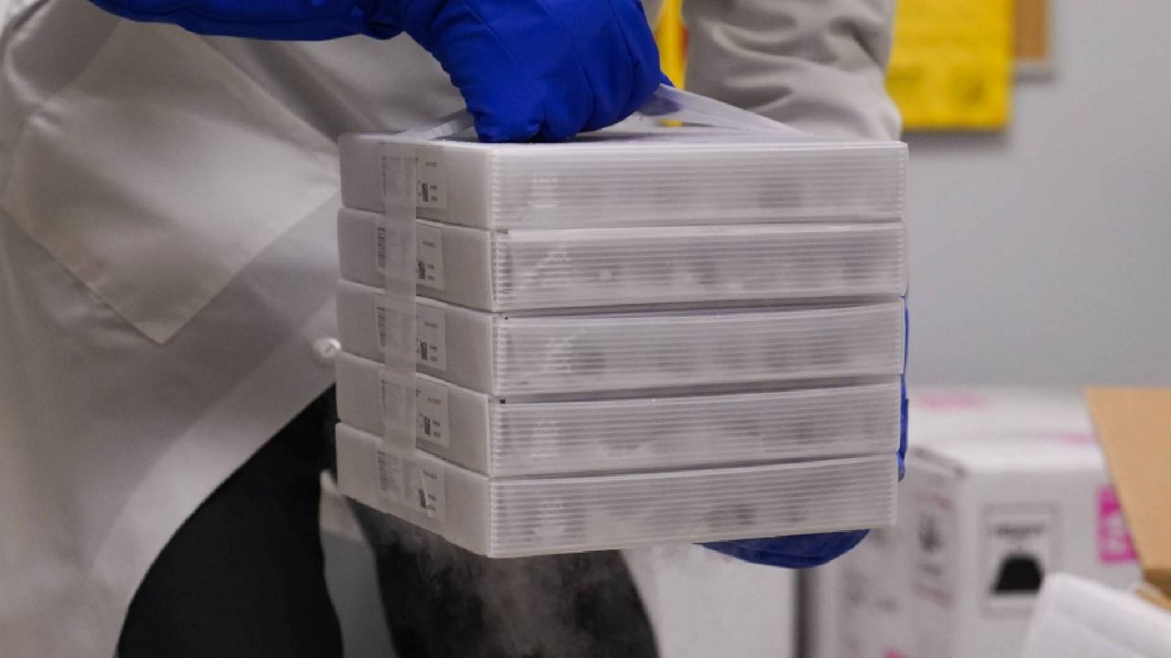 A pharmacy director pulls trays of the Pfizer-BioNTech COVID-19 vaccine out of a box in Los Angeles on Monday. (AP Photo/Jae C. Hong)