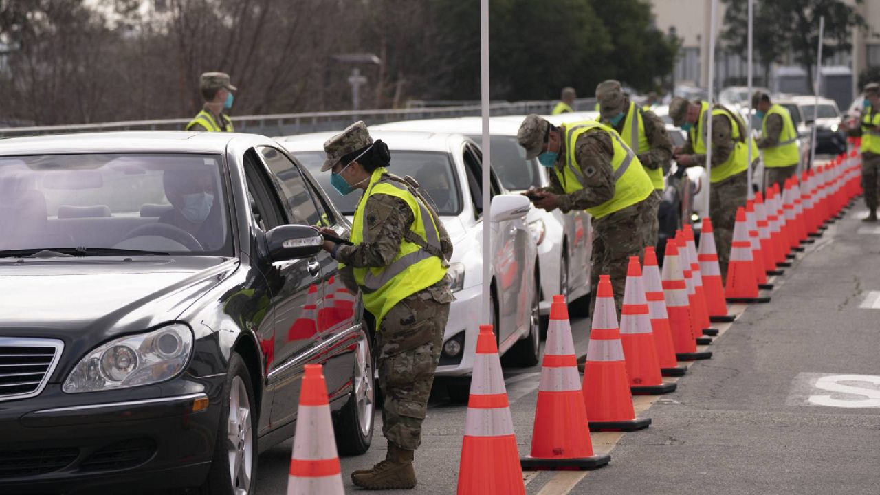 Members of the National Guard help motorists check in at a federally-run COVID-19 vaccination site set up on the campus of California State University of Los Angeles in Los Angeles, Tuesday, Feb. 16, 2021. (AP Photo/Jae C. Hong)