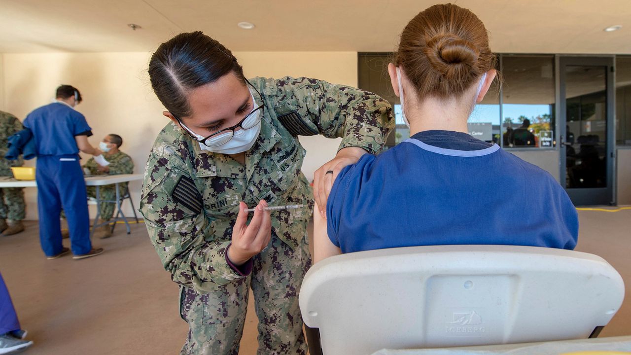 In this photo provided by the U.S. Navy, Petty Officer 2nd Class Jasmin Fiorini, a sailor assigned to Naval Medical Center San Diego (NMCSD), vaccinates a volunteering service member, Tuesday, Dec. 15, 2020. (Petty Officer 2nd Class Erwin Jacob V. Miciano/U.S. Navy via AP)
