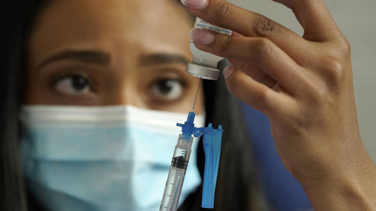 FILE - Licensed practical nurse Yokasta Castro, of Warwick, R.I., draws a Moderna COVID-19 vaccine into a syringe at a mass vaccination clinic, Wednesday, May 19, 2021, at Gillette Stadium, in Foxborough, Mass. (AP Photo/Steven Senne)