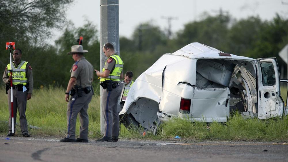 Texas Department of Public Safety officers stand near a vehicle where multiple people died after the van carrying migrants tipped over just south of the Brooks County community of Encino on Wednesday, Aug. 4, 2021, in Encino, Texas. (Delcia Lopez/The Monitor via AP)