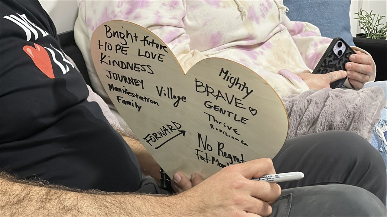 A Sense of Home volunteers write positive sentiment for furniture recipients on take-home wooden heart. (Spectrum News/Vania Patino)