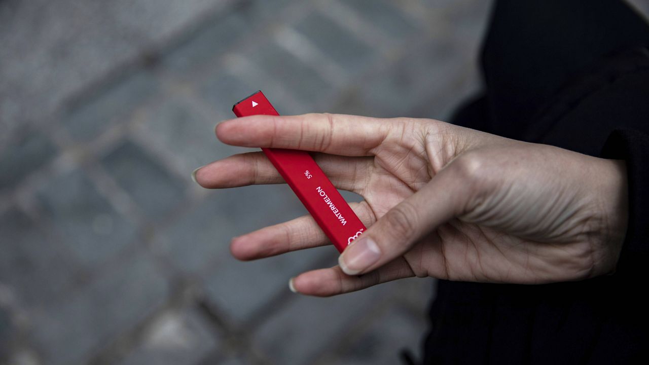 A woman holds a Puff Bar flavored disposable vape device. (AP Photo/Marshall Ritzel)
