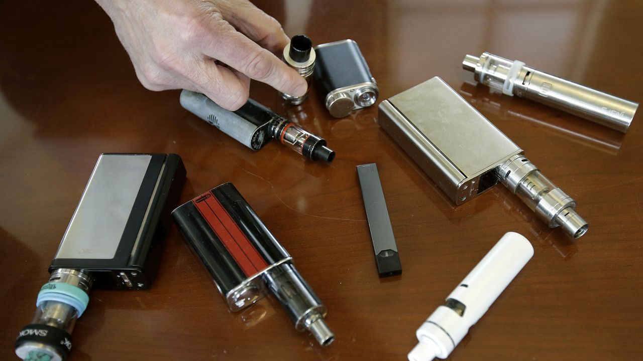 In this April 10, 2018 file photo, a high school principal displays vaping devices that were confiscated from students in such places as restrooms or hallways at the school in Massachusetts. (AP Photo/Steven Senne)