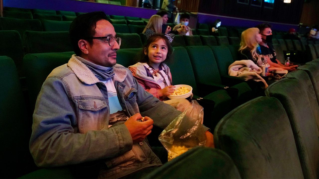 Anthony Helena, left, and his daughter Seraphin, 4, await a screening of the Disney animated film "Raya and the Last Dragon," Friday, March 19, 2021, in Los Angeles at El Capitan Theatre's reopening day following its shuttering more than a year ago due to the coronavirus pandemic. (AP Photo/Chris Pizzello)