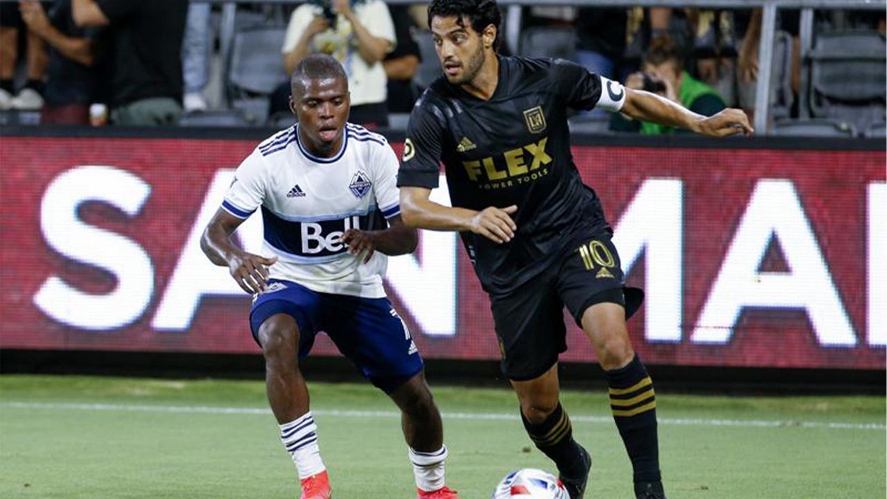 Los Angeles FC forward Carlos Vela (10) drives the ball past Vancouver Whitecaps midfielder Deiber Caicedo (7) during the second half of an MLS soccer match in Los Angeles, Saturday, July 24, 2021. The game ended in a 2-2 draw. (AP Photo/Ringo H.W. Chiu)