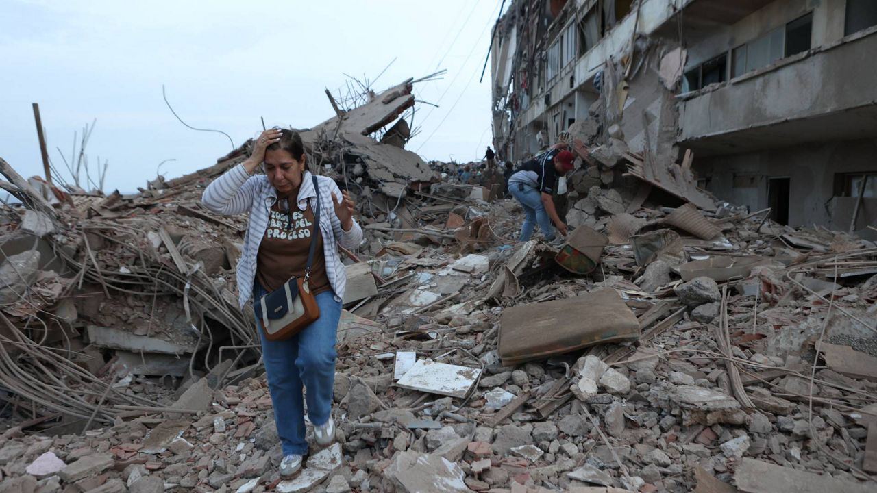 Residents walk among the rubble of building damaged in earthquakes the previous day in Catia La Mar, Venezuela, Thursday, June 25, 2026. (AP Photo/Pedro Mattey)