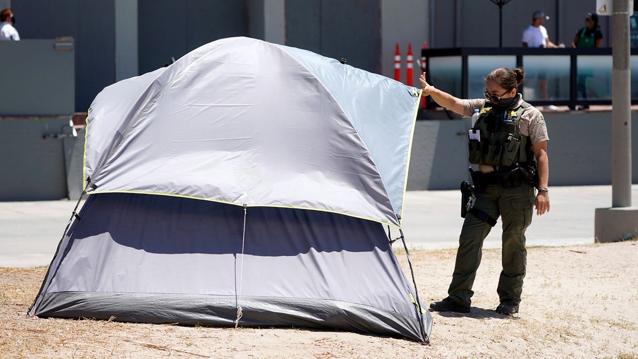 A member of Los Angeles County Sheriffs Department's HOST, Homeless Outreach Service Team, talks to a homeless person Tuesday, June 8, 2021, in the Venice Beach section of Los Angeles. (AP Photo/Marcio Jose Sanchez)