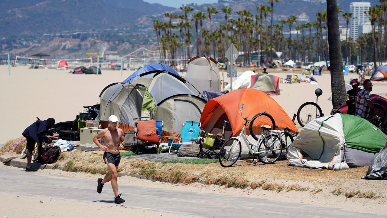 A jogger walks past a homeless encampment Tuesday, June 8, 2021, in the Venice Beach section of Los Angeles. (AP Photo/Marcio Jose Sanchez)