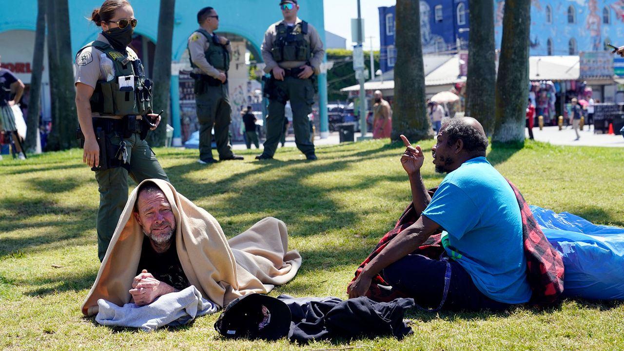 A member of the Los Angeles County Sheriffs Department's HOST, Homeless Outreach Service Team, talks to two homeless men Tuesday, June 8, 2021, in the Venice Beach section of Los Angeles. (AP Photo/Marcio Jose Sanchez)