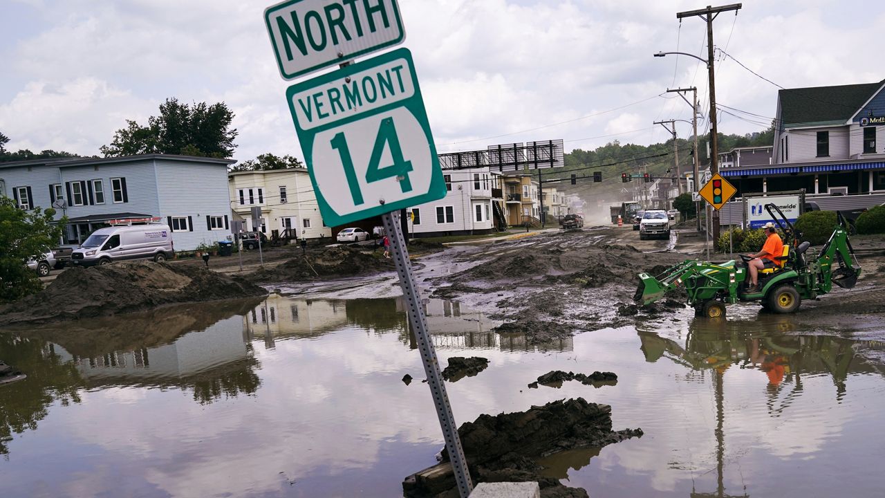 A small tractor clears water from a business as flood waters block a street, July 12, 2023, in Barre, Vt. (AP Photo/Charles Krupa, file)