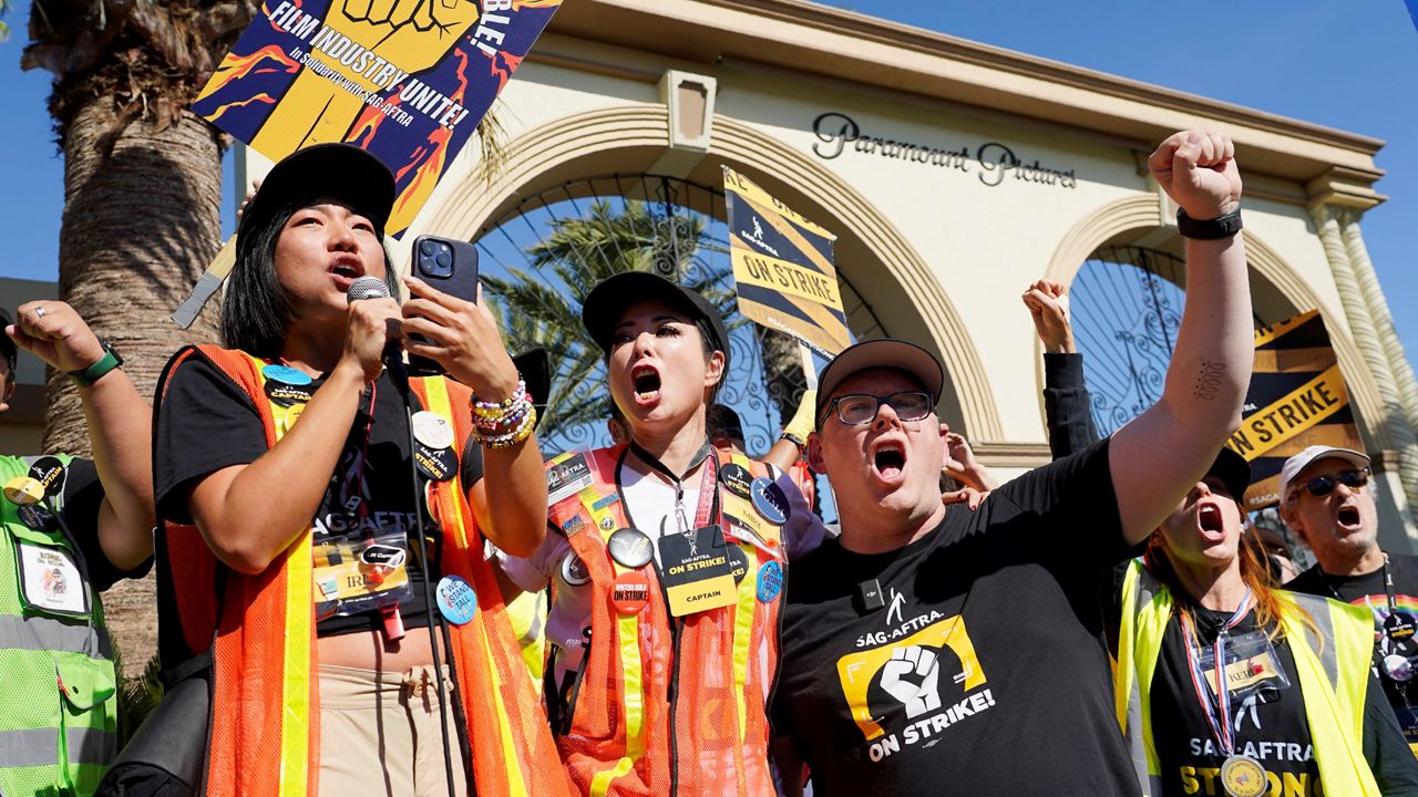 SAG-AFTRA captains Iris Liu, left, and Miki Yamashita, center, and SAG-AFTRA chief negotiator Duncan Crabtree-Ireland lead a cheer for striking actors outside Paramount Pictures studio on Nov. 3, 2023, in Los Angeles. (AP Photo/Chris Pizzello)