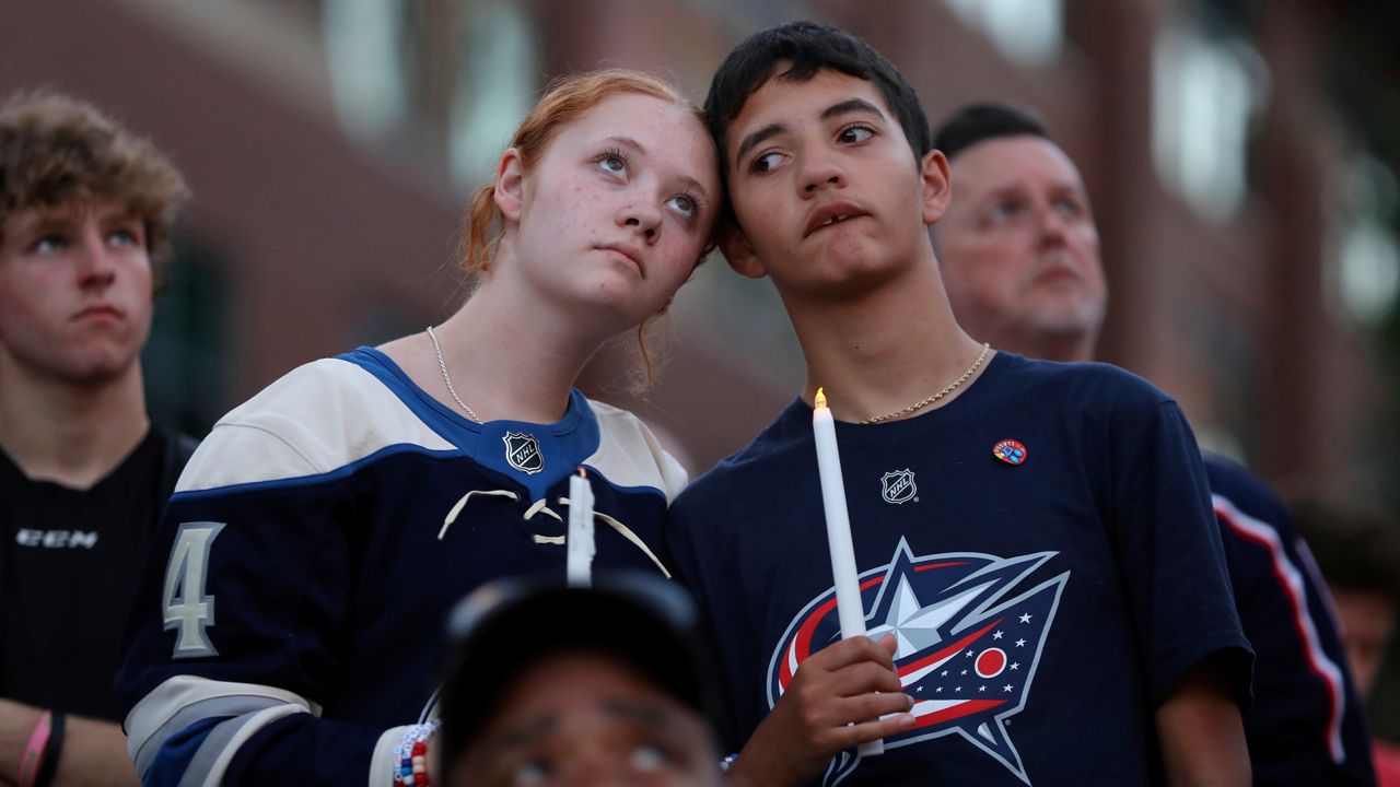 Blue Jackets fans Gianna,left, and Elijah Willis, have a moment of silence during the candlelight vigil to honor Columbus Blue Jackets hockey player Johnny Gaudreau, outside of Nationwide Arena in Columbus, Ohio, Thursday, Sept. 4, 2024.