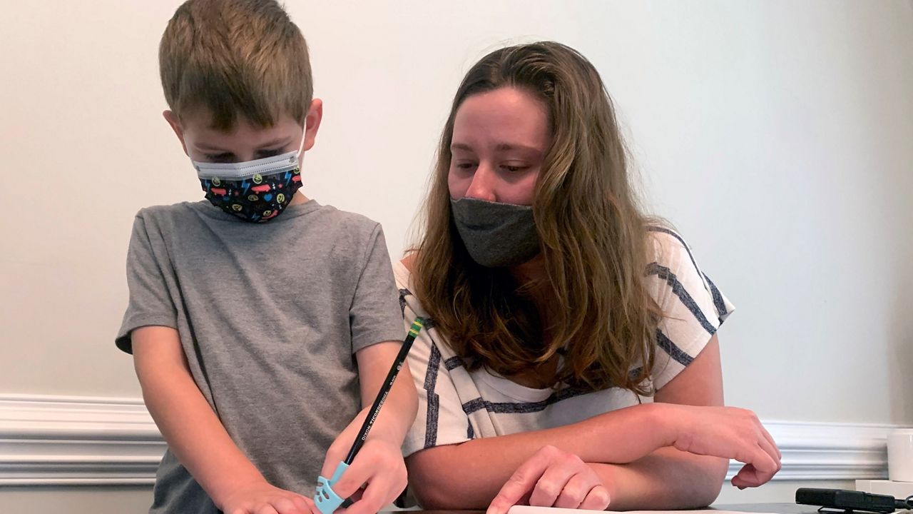 Emily Goss goes over school work at the kitchen table with her five-year-old son inside their Monroe, N.C., home on Monday, Sept. 13, 2021. (AP Photo/Sarah Blake Morgan)