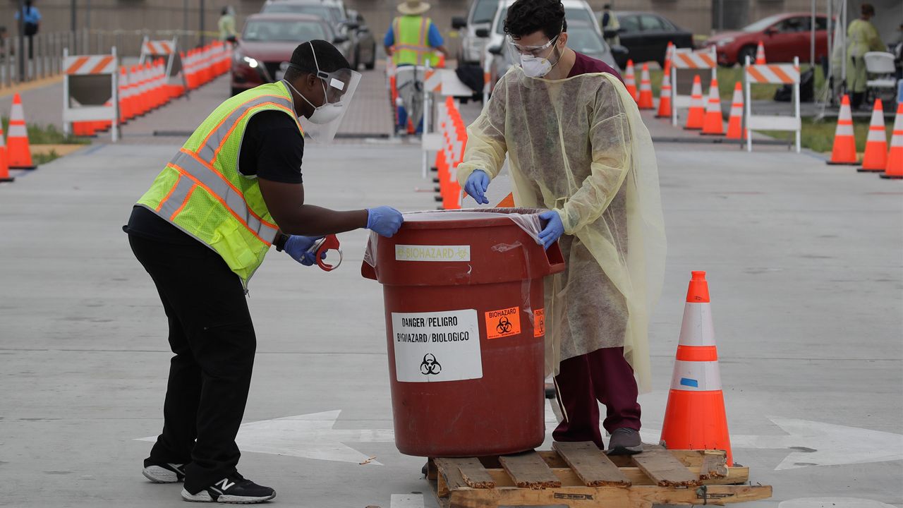 Workers collect samples at a mobile Coronavirus testing site at the Charles Drew University of Medicine and Science Wednesday, July 22, 2020, in Los Angeles. California's confirmed coronavirus cases have topped 409,000, surpassing New York for most in the nation. (AP Photo/Marcio Jose Sanchez)