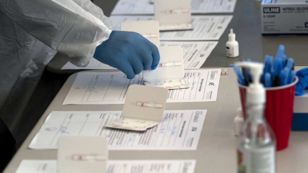 Nurse Ray Akindele processes COVID-19 rapid antigen tests at a testing site in Long Beach , Calif., Thursday, Jan. 6, 2022. (AP Photo/Jae C. Hong)