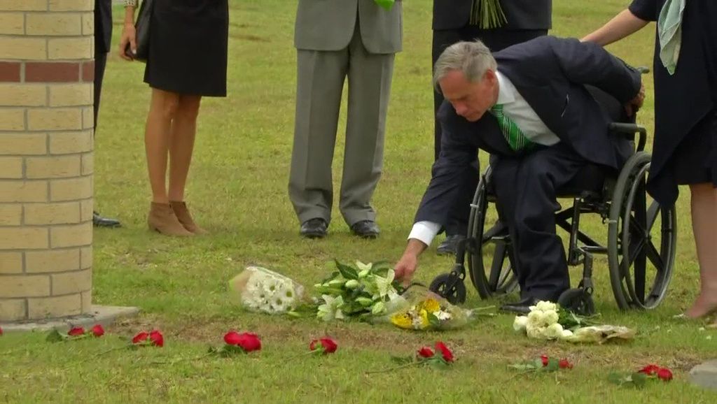 Texas Gov. Greg Abbott lays flowers on the ground in Sante Fe, Texas, in this image from May 2018. (Spectrum News)