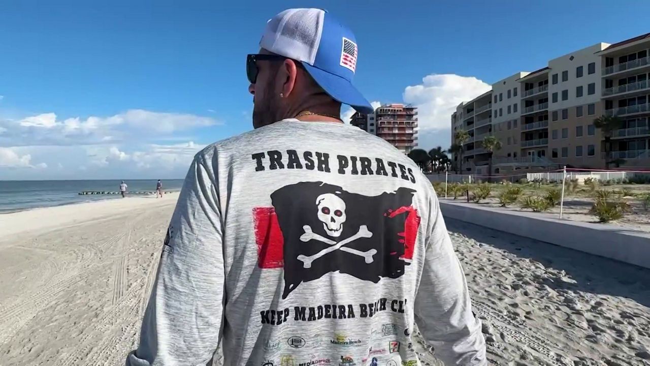 A volunteer with the Trash Pirates of Mad beach walks the shoreline look for litter following Fourth of July festivities. (Spectrum News)