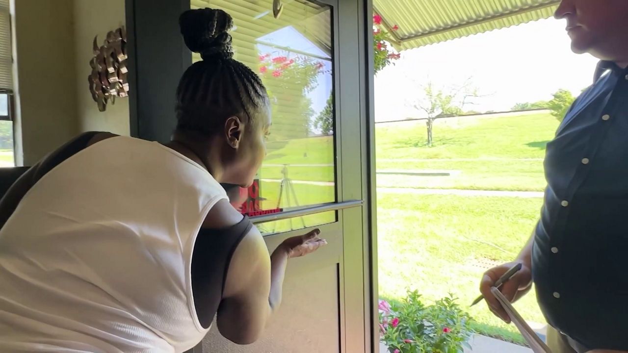 Tracey Paylor shows how high the water reached on her apartment door a day after floodwaters from Chantal invaded her home. (Spectrum News 1)