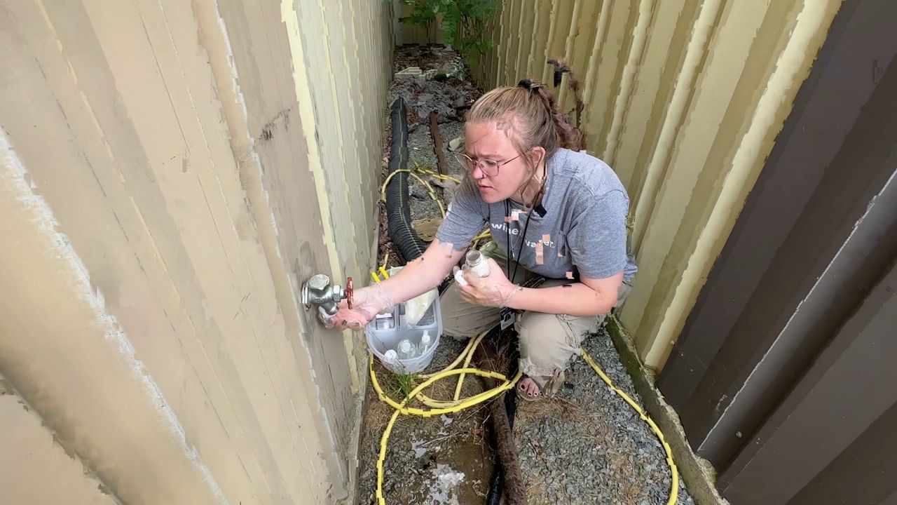 Eryn Stowe, a water quality specialist with Wine to Water, gathers water for a test in western North Carolina. (Spectrum News 1)