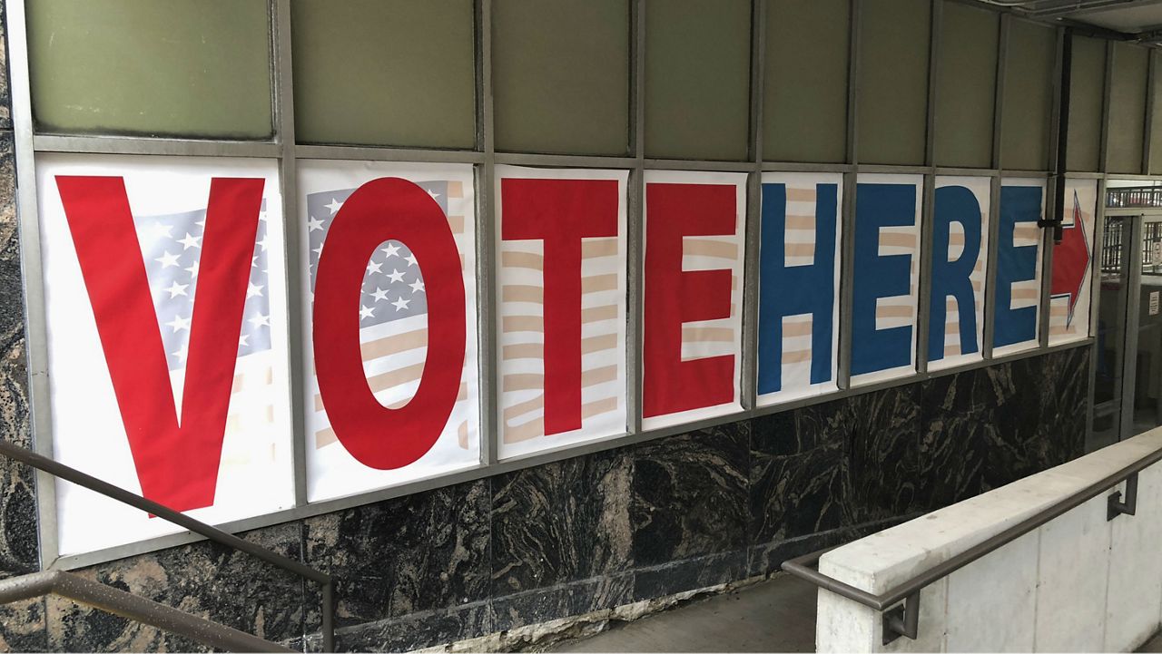 A sign reading "Vote Here" sign. (Photo Courtesy: Associated Press)