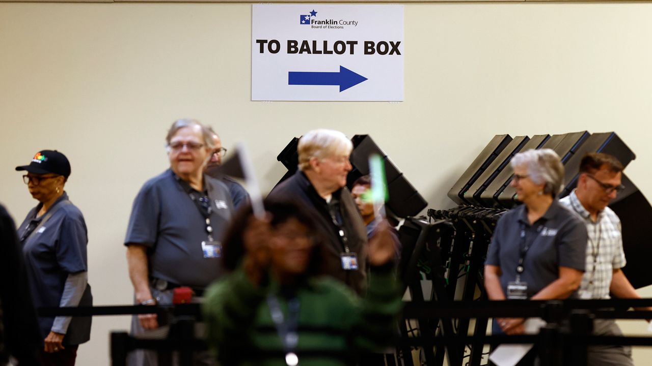 Poll workers wait to escort voters to the polling booths during the first day of in person early voting at the Franklin County Board of Elections in Columbus, Ohio, Tuesday, Oct. 8, 2024. (AP Photo/Paul Vernon)