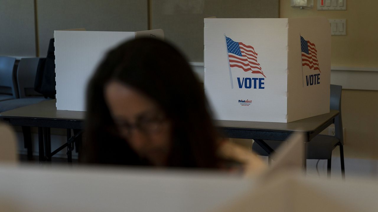 A voter in the foreground casts her ballots during the Republican primary election in Wilson, Wyo., Aug. 16, 2022. 