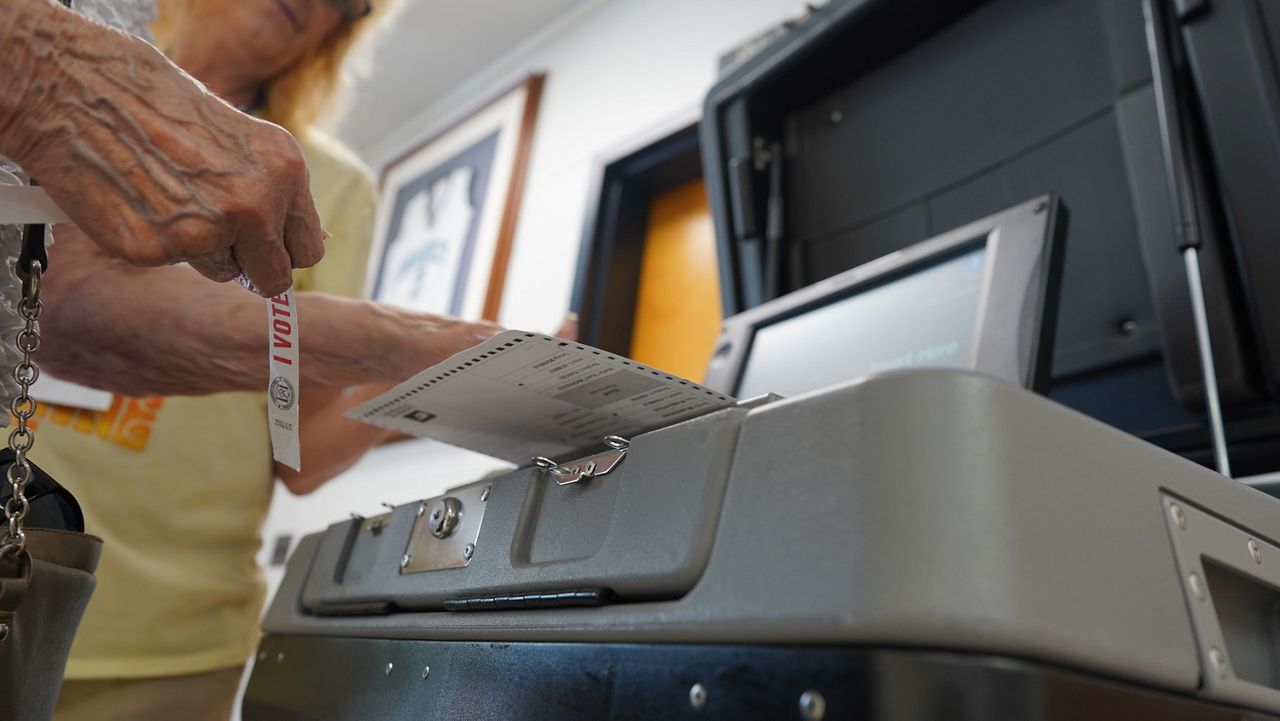 A voter inserts their paper ballot into the voting machine of a Louisville, Ky. polling location. (Spectrum News/Jonathon Gregg)