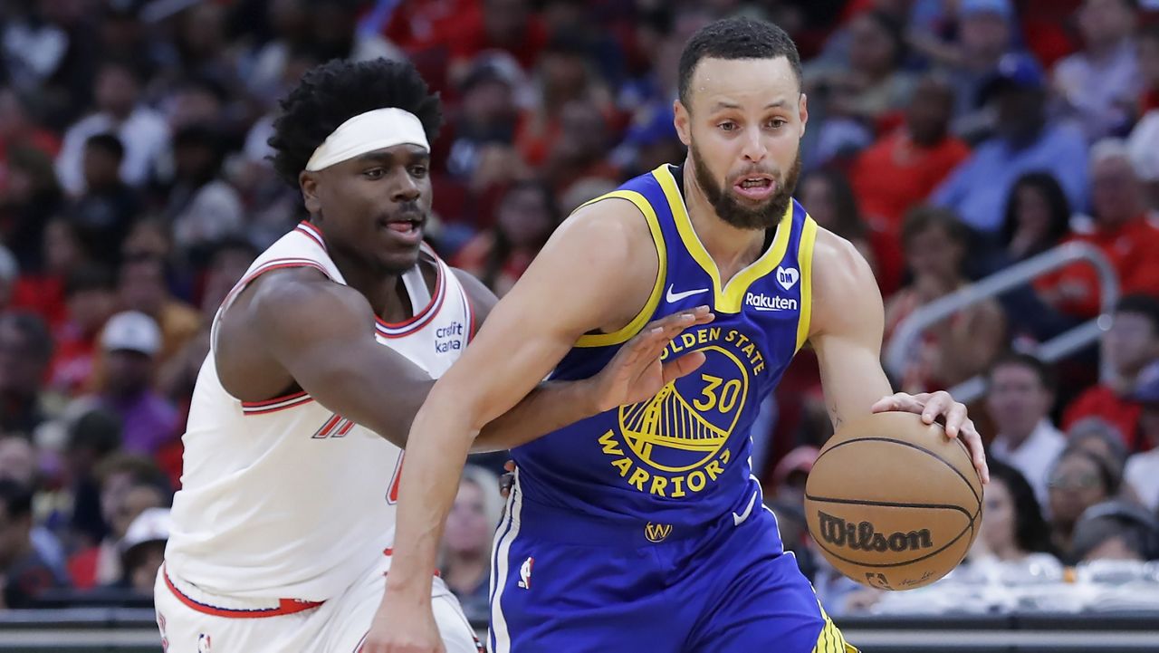 Golden State Warriors guard Stephen Curry, right, drives to the basket as Houston Rockets guard Aaron Holiday, left, reaches in during the second half of an NBA basketball game Thursday, April 4, 2024, in Houston. (AP Photo/Michael Wyke)