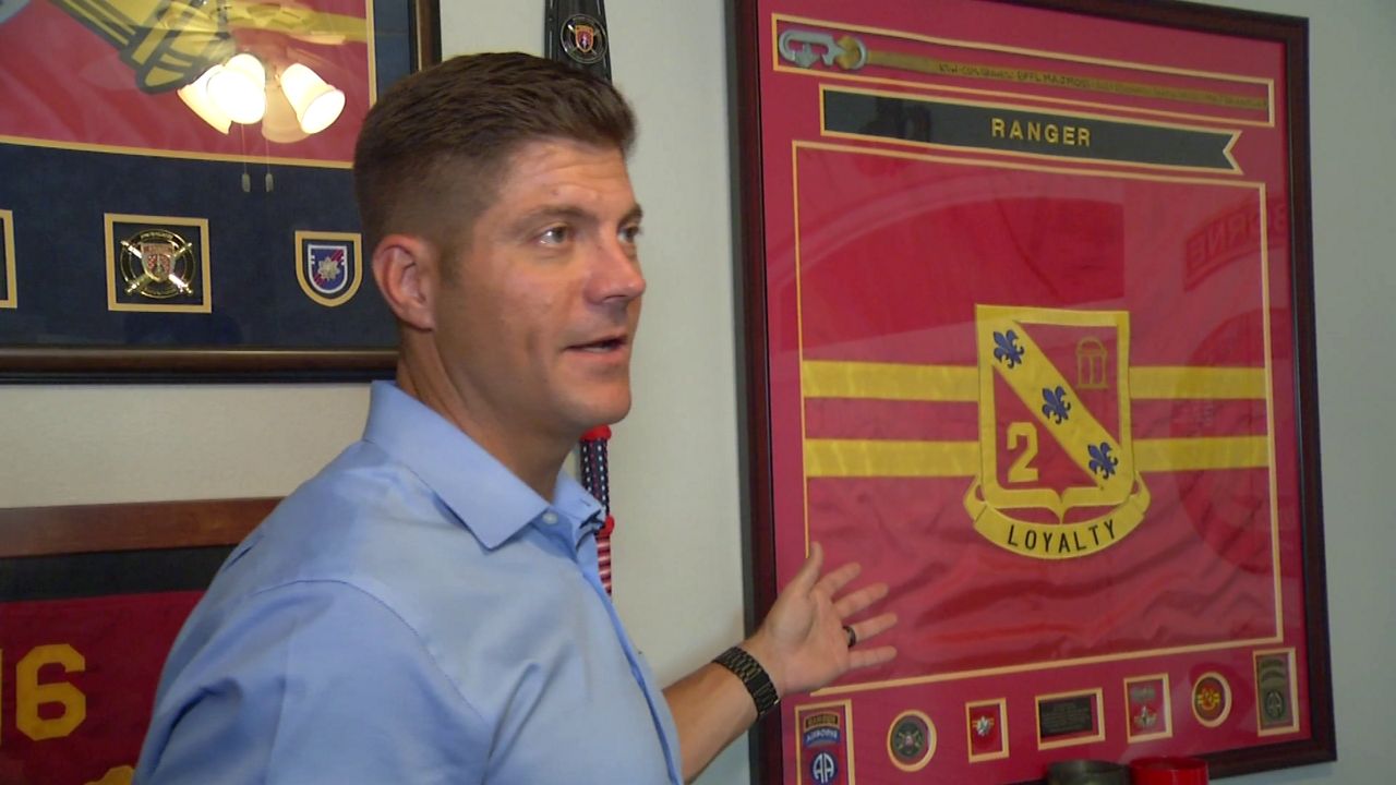 Wayne Fogel says a flag posted up in his home office symbolizes one of his fondest memories from his service – when he got the chance to command a field artillery battalion in the 82nd Airborne Division. (Spectrum News)