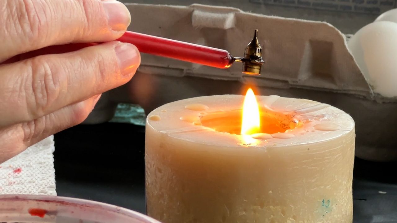 Sobiskova holding tool over lit candle.