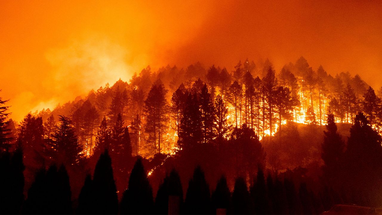 In this Sept. 27, 2020 file photo the Glass Fire burns a hillside above Silverado Trail in St. Helena, Calif. Dry, windy weather posed an extreme wildfire risk Wednesday, Oct. 14, 2020, in Northern California, where massive blazes already have cost hundreds of homes and killed or injured dozens of people. (AP Photo/Noah Berger, File)